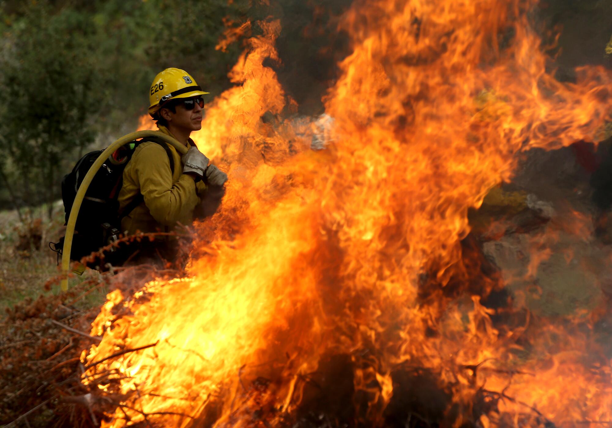 A firefighter stands near burning debris.