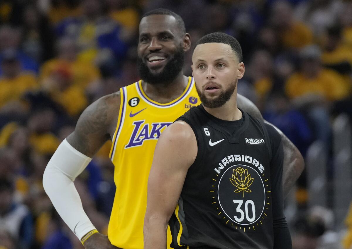 Lakers star LeBron James, left, and Golden State Warriors star Stephen Curry stand on the court.
