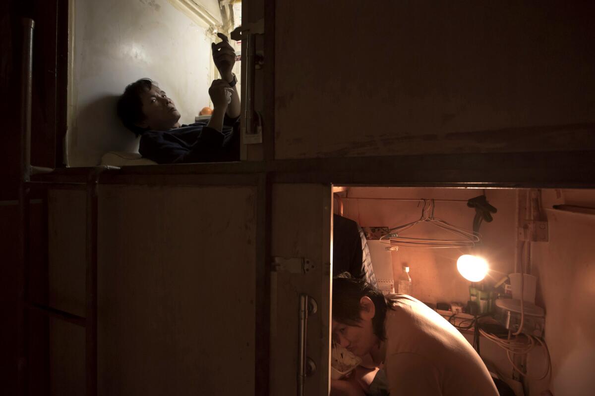 Residents who only gave their surnames Yeung, left and Lui, rest in their "coffin homes" in Hong Kong.