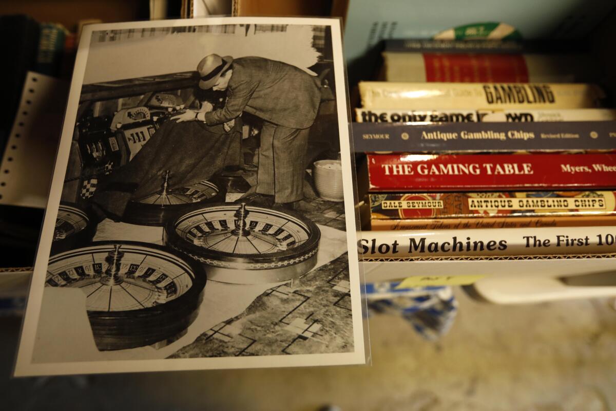 A photograph of a law enforcement agent examining roulette wheels confiscated from the S.S. Rex rests on a box of books.