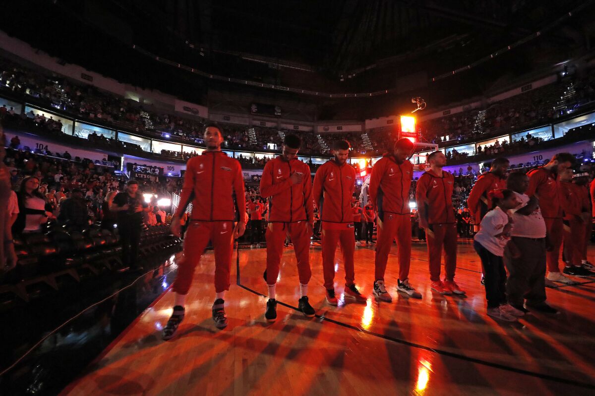 CORRECTS SPELLING TO CARLEY, INSTEAD OF CARLY - The New Orleans Pelicans pause during a moment of silence for Carley McCord, a sports journalist who was the in-game host for the Pelicans and who died in a plane crash Saturday, before the team's NBA basketball game against the Indiana Pacers in New Orleans, Saturday, Dec. 28, 2019. McCord, the daughter-in-law of LSU football offensive coordinator Steve Ensminger, had just departed Lafayette, La., en route to the Peach Bowl in Atlanta, where LSU was playing Oklahoma, when the plane crashed, killing five people. (AP Photo/Gerald Herbert)