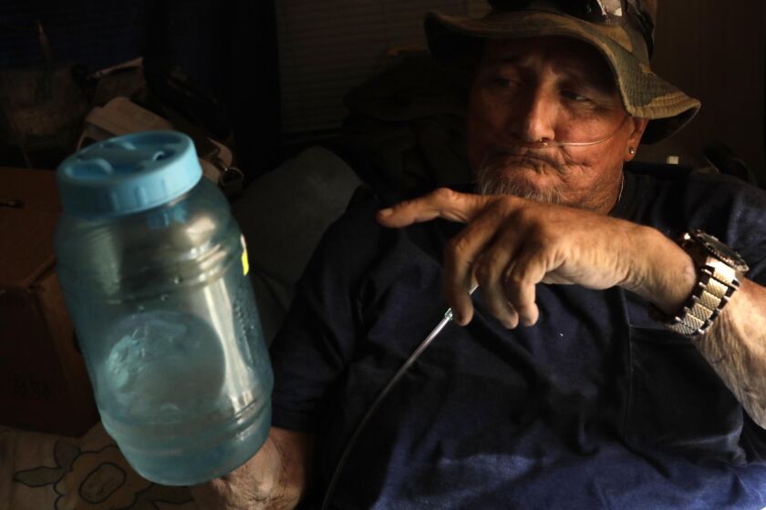 DESERT HOT SPRINGS, CA - MAY 26, 2021 - - Allan Wanner, on oxygen, tries to stay cool by drinking melted ice cubes from a plastic container in his trailer at Corkill Park RV & Mobile Homes in Desert Hot Springs on May 26, 2021. Wanner, who lives alone, is only allowed 1500 milliliters of water a day because he is on Lasix for retaining water. When temperatures rise living conditions can get dangerous for residents of the trailer park. Warner suspects his neighbor Jerry Floyd died from heat related causes in 2020. It was Wanner who found him dead in a trailer and he still mourns his death. He has since moved to Arizona where he believes temperatures are not as extreme in the summer. He suffers from congestive heart failure, diabetes and other ailments and his health is jeopardized when temperatures go above 100 degrees. According to Los Angeles County Coroner's and Medical Offices, hundreds of heat-related deaths reviewed by the Times showed the victims included seniors who died alone in apartments without air conditions, or with the thermostat off. (Genaro Molina / Los Angeles Times)