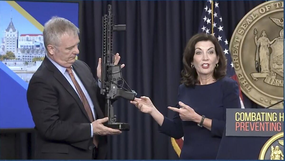 In this image taken from video, Kevin Bruen, Superintendent of the New York State Police, holds a firearm as New York Gov. Kathy Hochul speaks during a news conference, Wednesday, May 18, 2022, in New York. New York would require state police to seek court orders to keep guns away from people who might pose a threat to themselves or others under a package of executive orders and gun control bills touted Wednesday by Hochul in the aftermath of a racist attack on a Buffalo supermarket. (Office of the Governor of New York via AP)