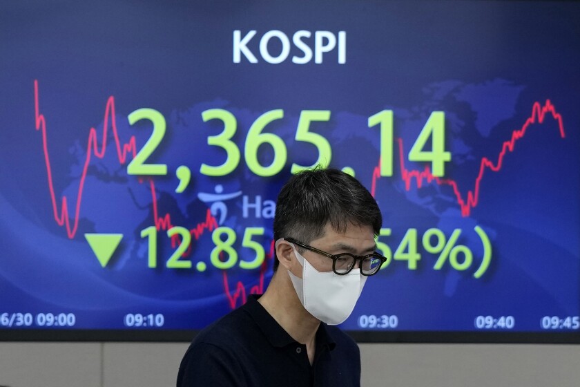 A currency trader walks by the screen showing the Korea Composite Stock Price Index (KOSPI) at a foreign exchange dealing room in Seoul, South Korea, Thursday, June 30, 2022. Asian stock markets were mixed Thursday after the U.S. economy contracted and China reported stronger factory activity.(AP Photo/Lee Jin-man)