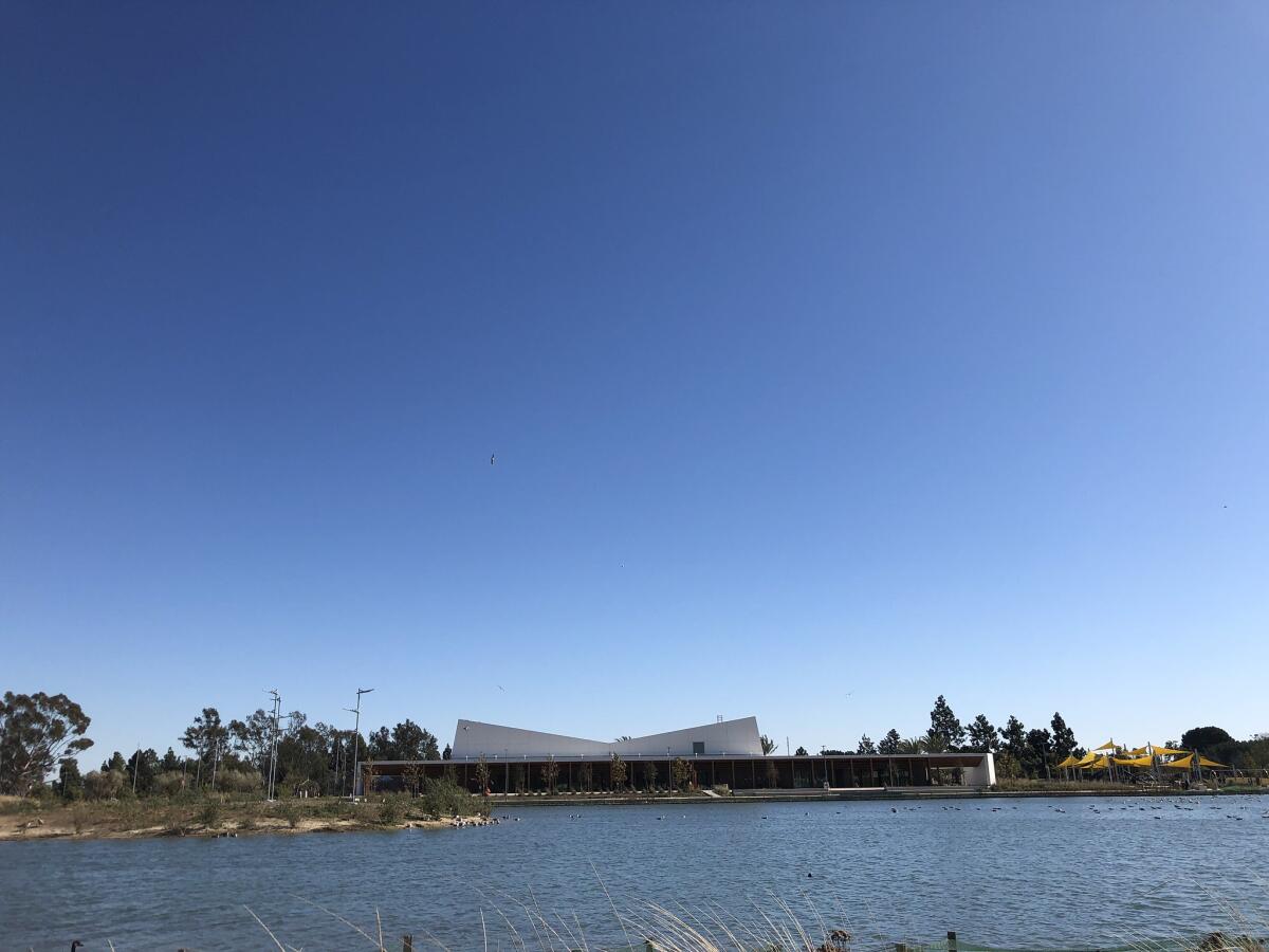 A view across a lake to a building with a tilted roofline.