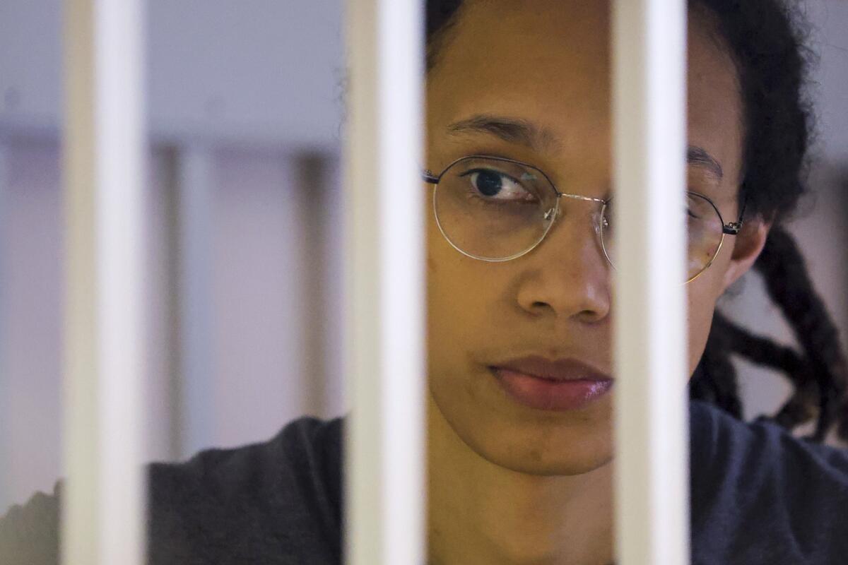 Brittney Griner looks through bars of a cage in a courtroom outside Moscow.