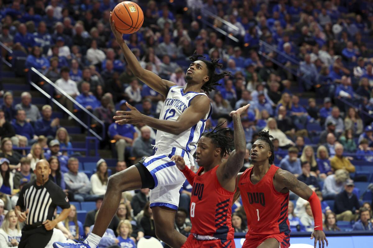 Kentucky's Antonio Reeves (12) shoots near Duquesne's Tevin Brewer (0) and Jimmy "Tre" Clark III (1) during the second half of an NCAA college basketball game in Lexington, Ky., Friday, Nov. 11, 2022. (AP Photo/James Crisp)