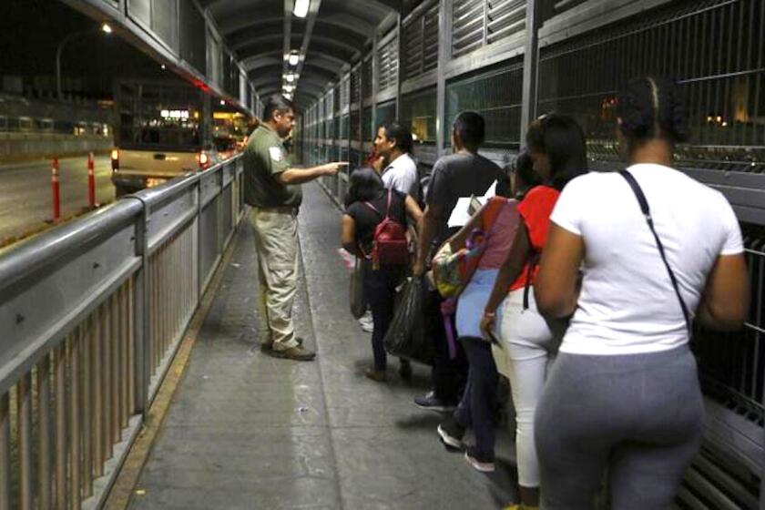 Un agente migratorio mexicano da instrucciones a migrantes que están solicitando asilo en Estados Unidos mientras aguardan en el Puente Internacional 1 en Nuevo Laredo, México, para ingresar a Laredo, Texas.