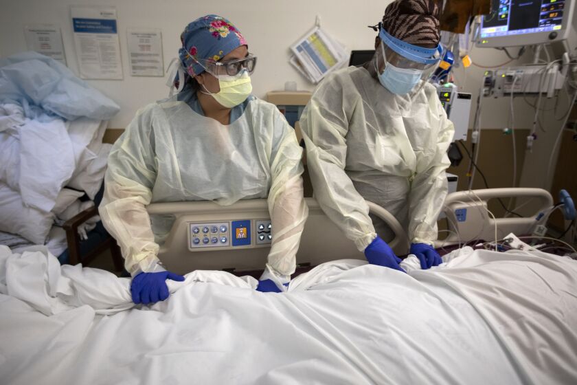 MISSION HILLS, CA - DECEMBER 29: Registered Nurse Melissa Brawley, left, and Registered Nurse Ashley Gould, right, moves a covid patient from his stomach to his back inside the ICU Providence Holy Cross Medical Center on Tuesday, Dec. 29, 2020 in Mission Hills, CA. Juan is a patient inside the covid unit (Francine Orr / Los Angeles Times)