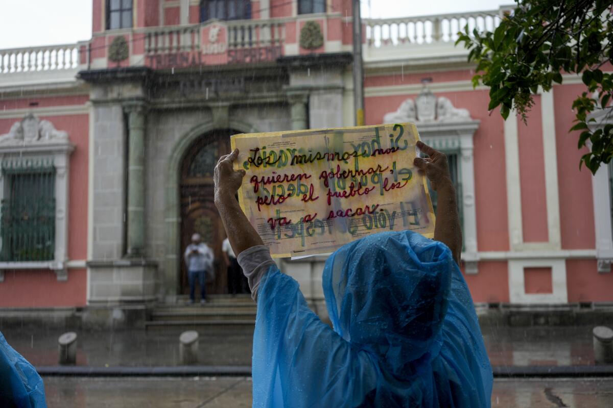 A person holds a sign in front of the electoral court building in Guatemala City during a protest.