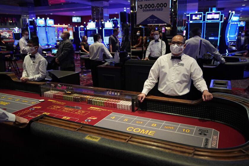 Dealers in masks wait for customers before the reopening of the D Las Vegas hotel and casino, Wednesday, June 3, 2020, in Las Vegas. Casinos were allowed to reopen on Thursday after temporary closures as a precaution against the coronavirus. (AP Photo/John Locher)