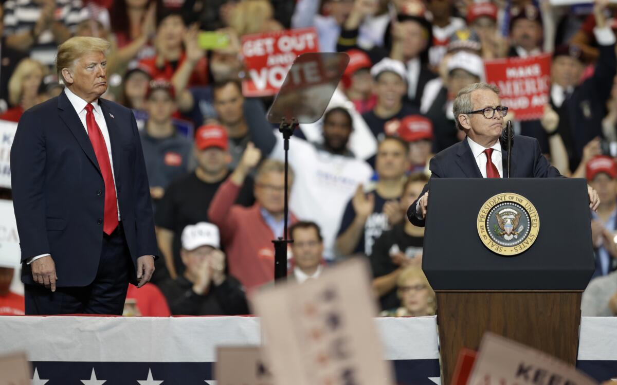 FILE - President Donald Trump listens as Ohio gubernatorial candidate Mike DeWine speaks at a campaign rally on Nov. 5, 2018, in Cleveland. According to a statement Wednesday, Sept. 7, 2022, former President Donald Trump has endorsed DeWine in his reelection bid after deciding against openly backing him in the primary. (AP Photo/Tony Dejak, File)