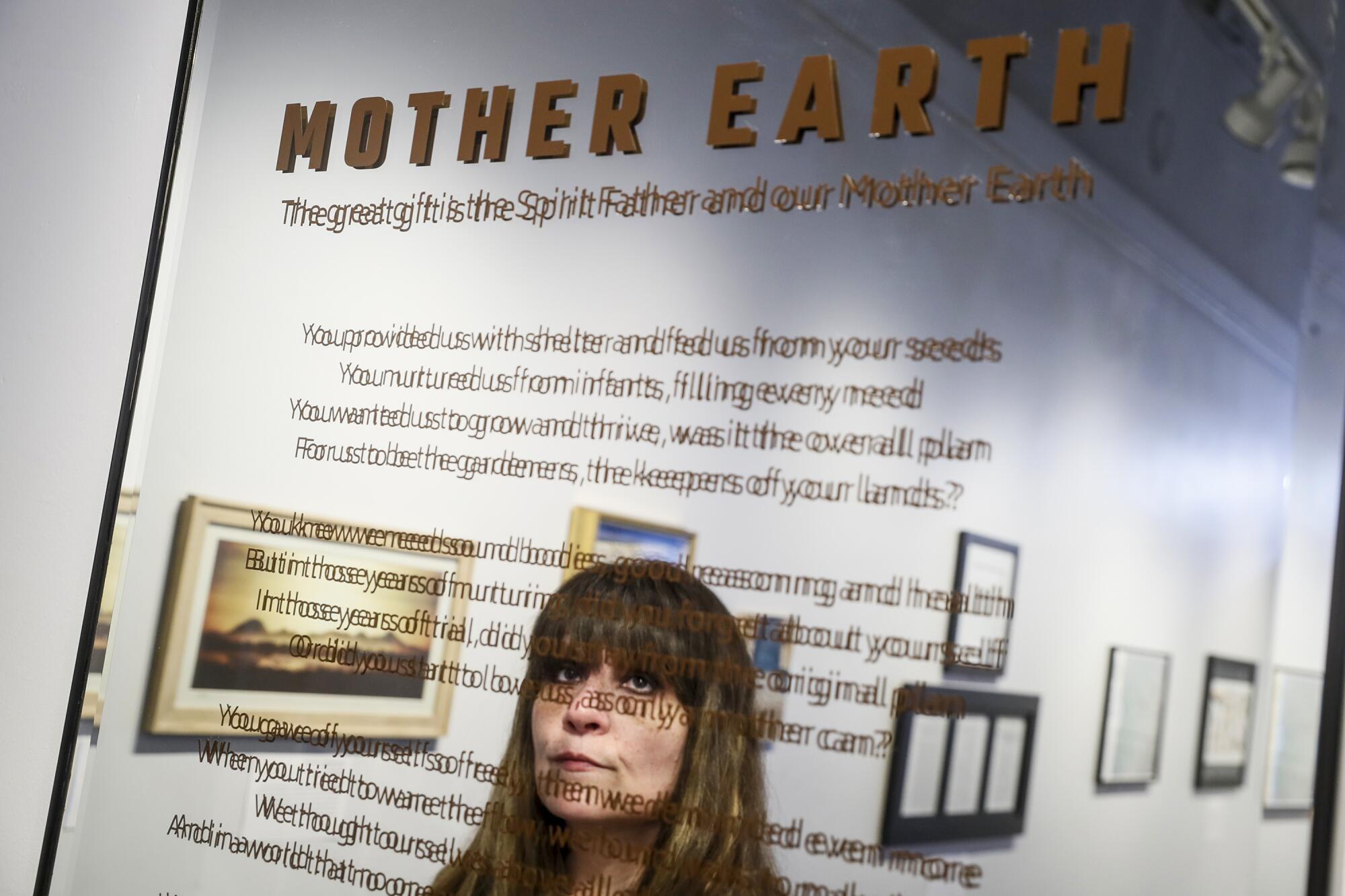 A woman's face reflected in a mirrored surface with a message on it 