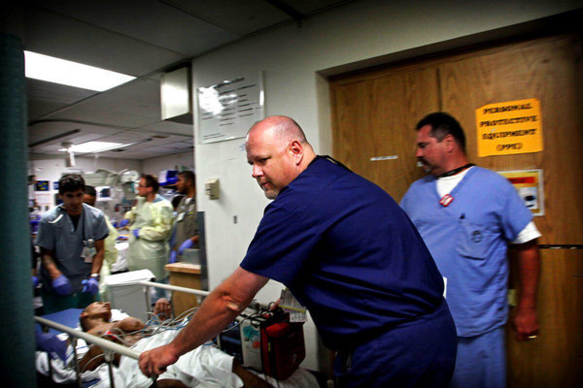 Dr. Brant Putnam helps wheel the wounded youth to the operating room.