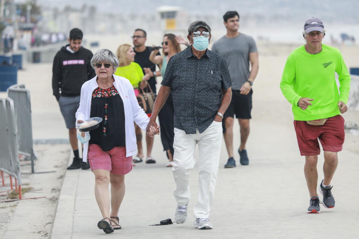 La gente camina por el paseo marítimo de Pacific Beach el miércoles 12 de mayo de 2021.