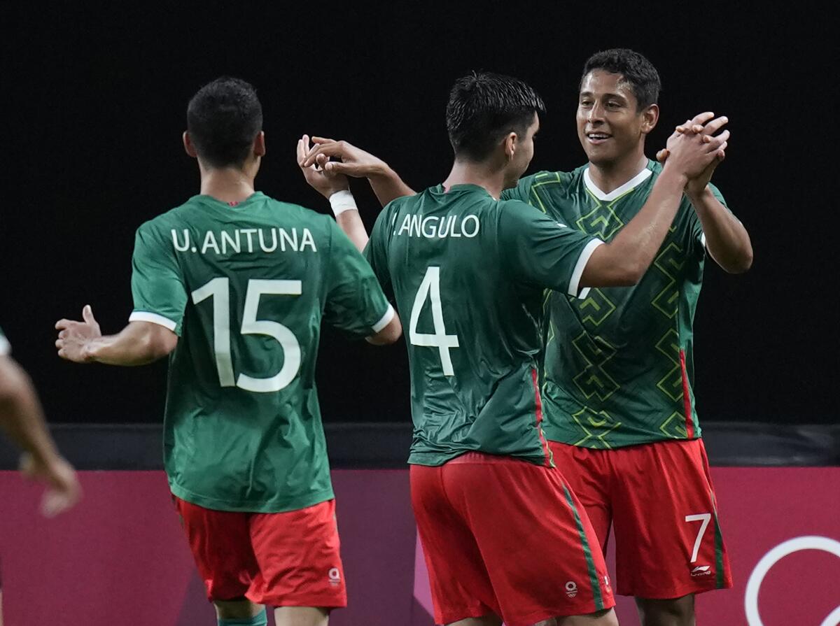 Luis Romo of Mexico's men's soccer team clasps hands with teammates at the Tokyo Olympics.