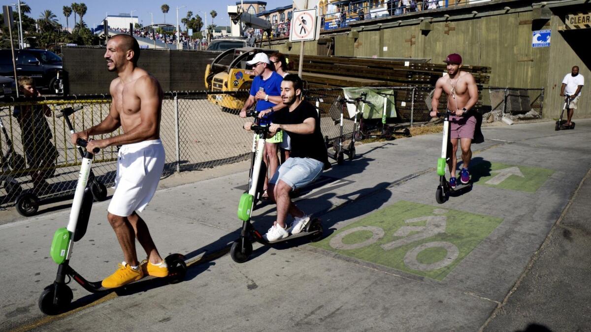 People ride Lime and Bird scooters along the strand in Santa Monica last year. The Burbank City Council unanimously voted on Tuesday to continue a prohibition against the use of shared-use mobility devices from companies such as Bird and Lime.