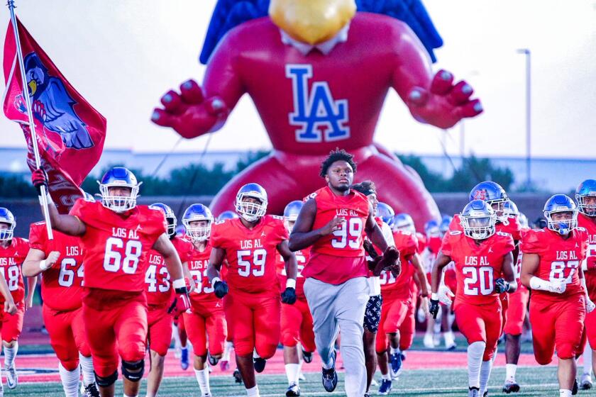 Ineligible T.A. Cunningham (99) leads out Los Alamitos on Thursday night against Santa Margarita.