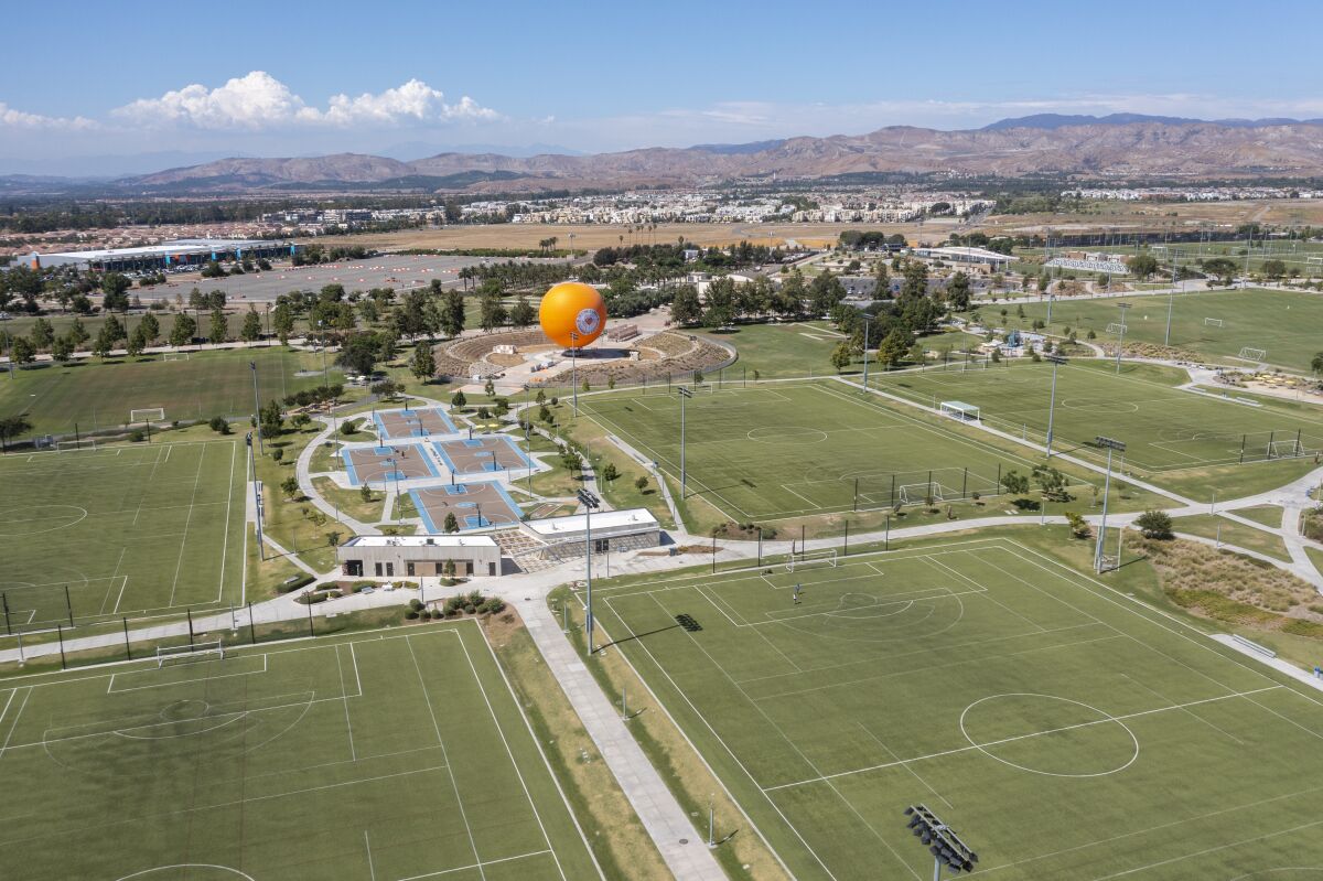 An aerial view of a park with soccer fields, basketball courts and a large orange balloon