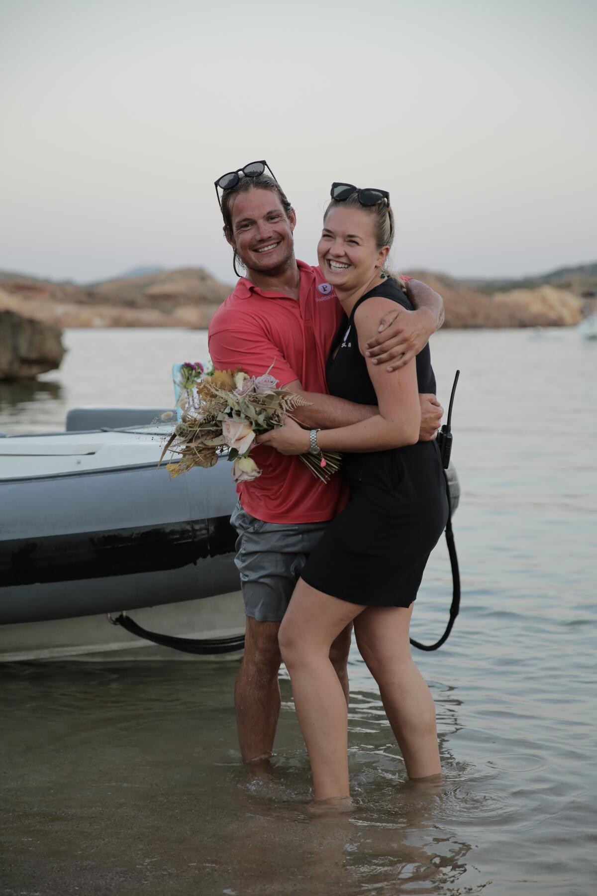 A couple standing by a dinghy by the shore