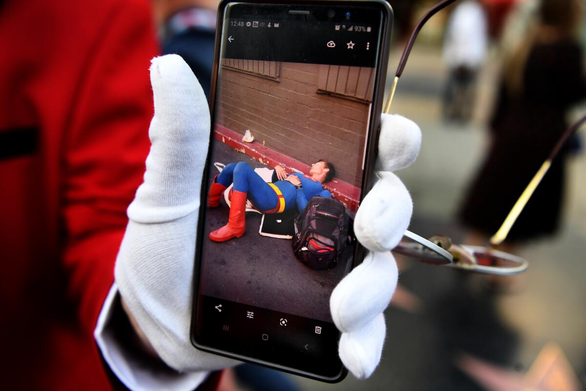 Gregg Donovan, who works for L.A. City Tours, shows a picture he photographed of Christopher Dennis, known as the Hollywood Boulevard Superman, some time before his death.