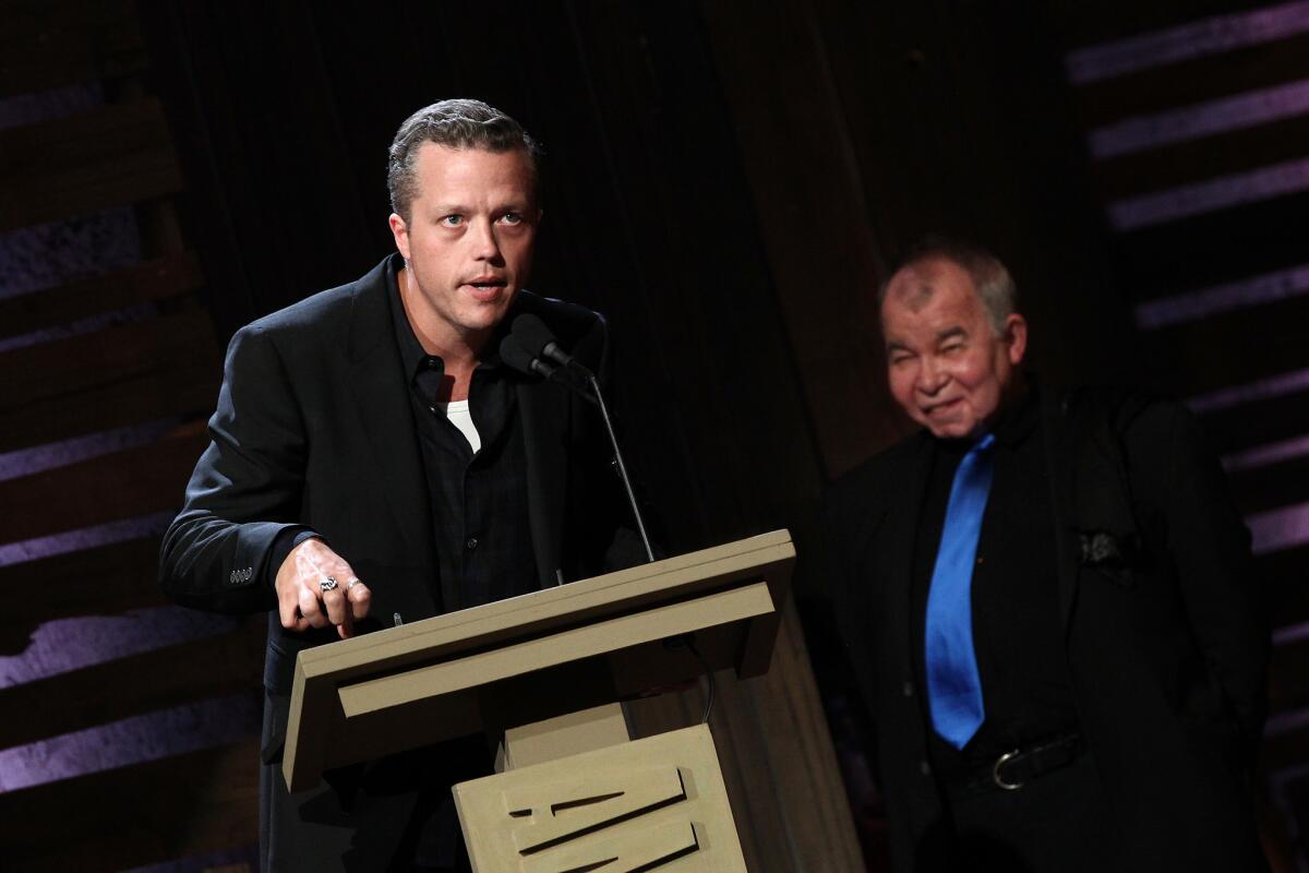 Jason Isbell accepts the Americana Music Assn's album of the year award, with presenter John Prine looking on.
