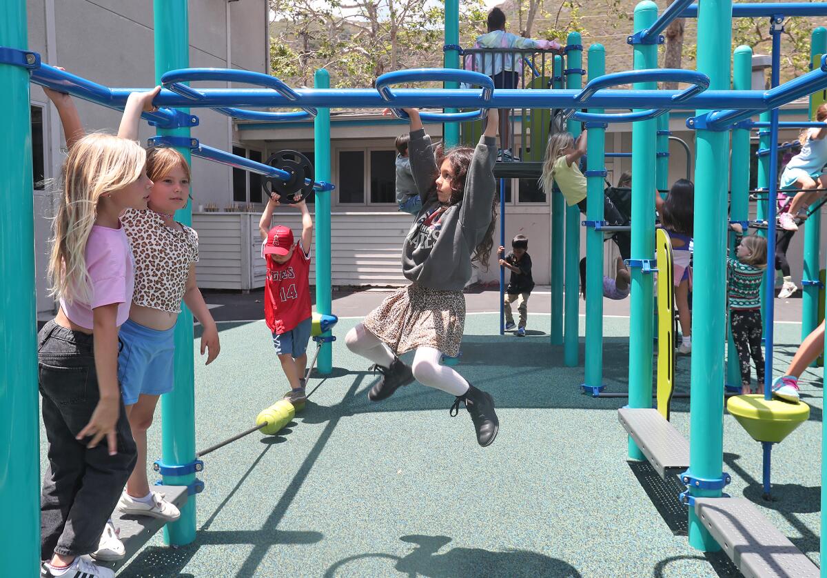 Kids from the Boys & Girls Club of Laguna Beach jump on the fixed rings at the new Dream Play Yard on Friday.