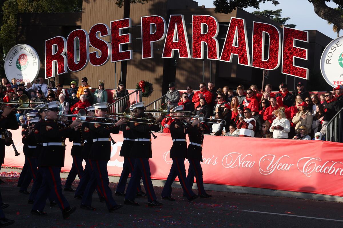 A Marine Corps marching band passes under a Rose Parade banner