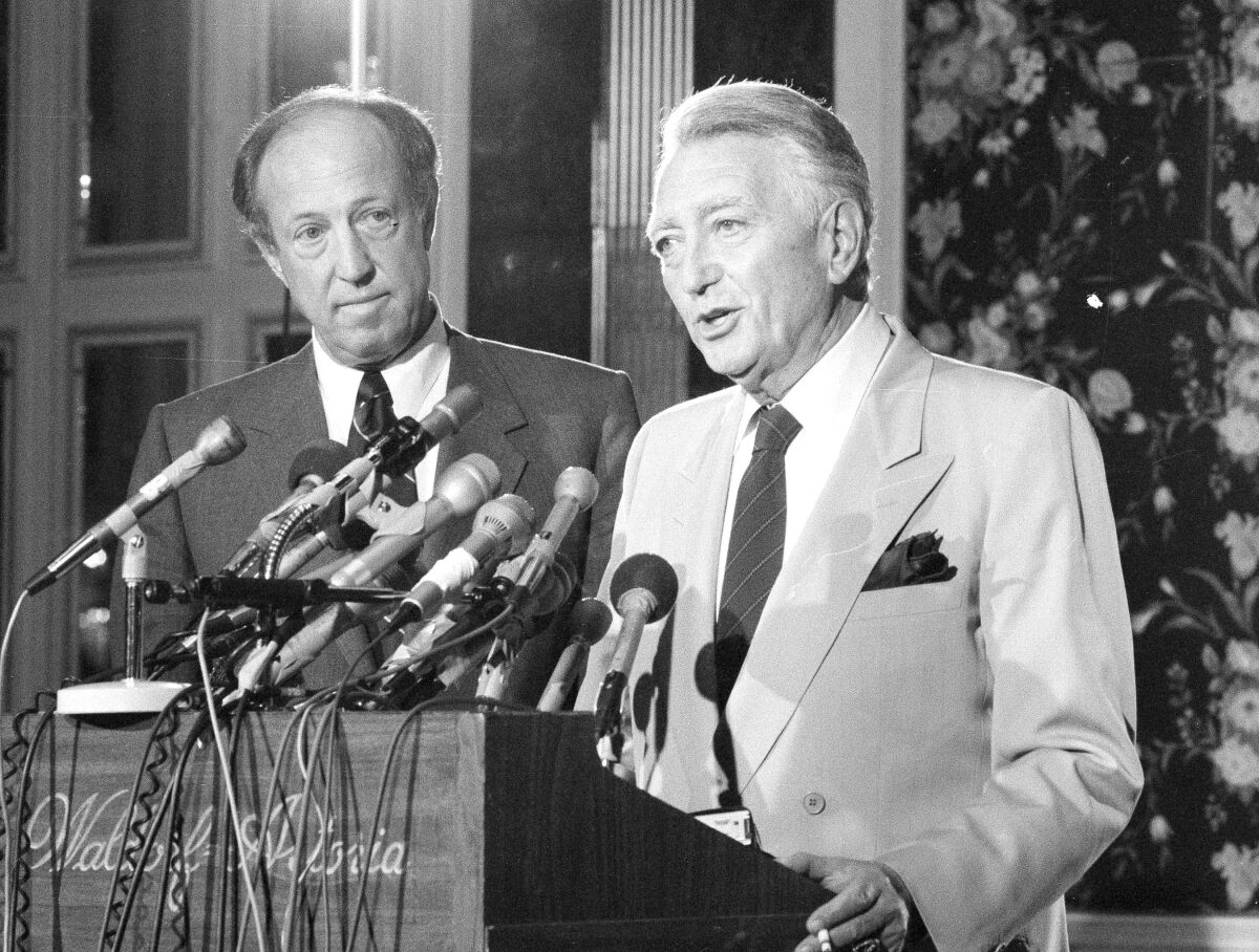Philadelphia Eagles owner Leonard Tose speaks into microphones as NFL commissioner Pete Rozelle watches.