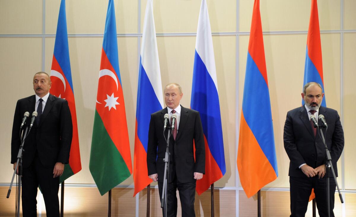 The Azerbaijani, Russian and Armenian government leaders stand in front of flags
