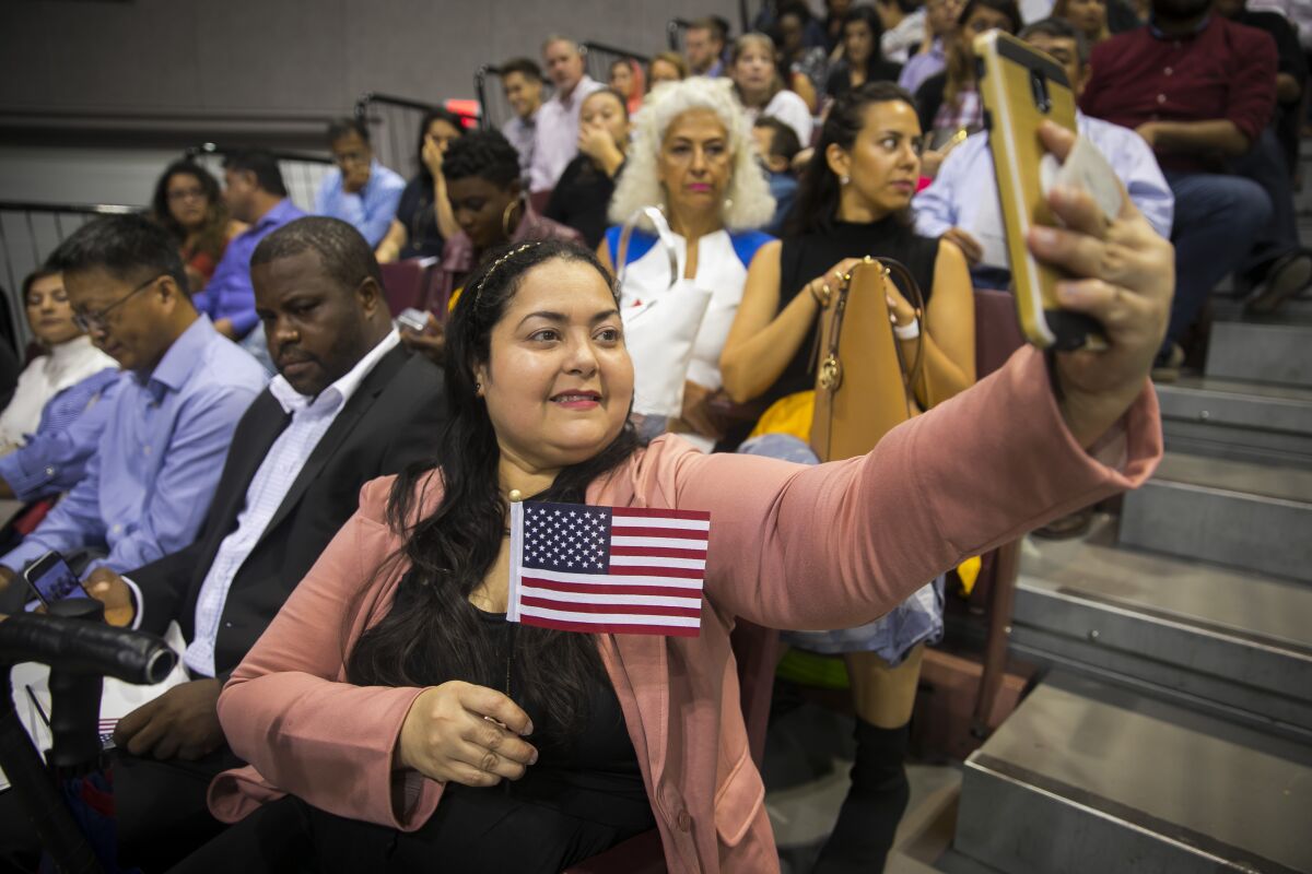 Nirhosky Griffin takes a selfie with a small American flag as she waits for her naturalization ceremony to begin in Houston.