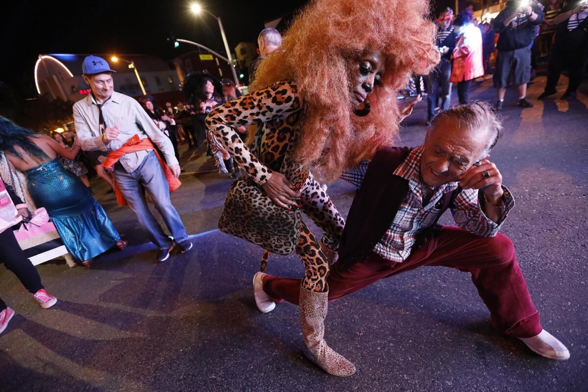 Dolly Boyd, center, dances with Abbas Hashei, 74, right, while joining the thousands of costumed revelers at the Halloween Carnaval.