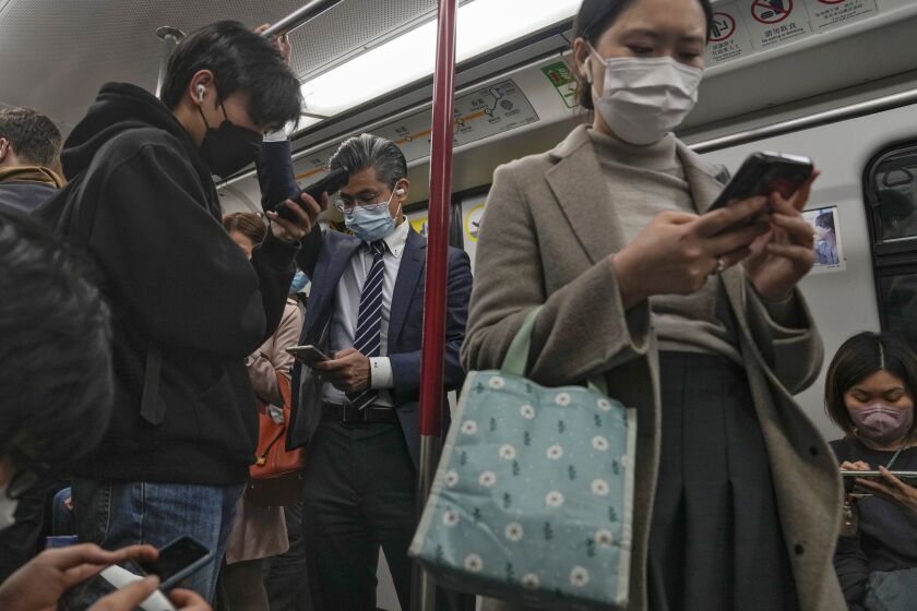 FILE - Commuters wearing face masks browse their smartphones as they ride on a subway train in Hong Kong on Feb. 7, 2023. Hong Kong will lift its mask mandate Wednesday, March 1, 2023, ending the city’s last major restriction imposed during the COVID-19 pandemic. (AP Photo/Andy Wong, File)
