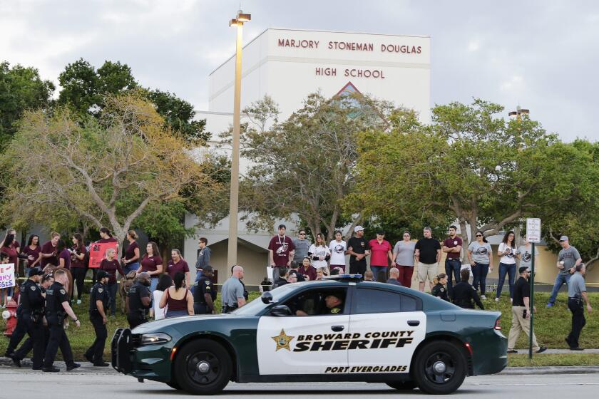 FILE - In this Feb. 28, 2018 photo, a police car drives by Marjory Stoneman Douglas High School in Parkland, Fla., as students returned to class for the first time since a former student opened fire there with an assault weapon. Vice President Kamala Harris will tour on Saturday, March 23, 2024, the blood-stained classroom building where the 2018 Parkland high school massacre happened, accompanied by some victims' family members who are pushing for stricter gun laws and improved school safety. (AP Photo/Terry Renna, File)