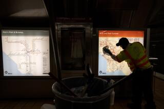 NORTH HOLLYWOOD, CALIF. -- THURSDAY, MARCH 26, 2020: A LA Metro custodian cleans a transit map inside the Metro Red Line's North Hollywood station in North Hollywood, Calif., on March 26, 2020. Metro has strengthened its cleaning regimes of buses, trains and facilities in the face of the coronavirus pandemic. (Brian van der Brug / Los Angeles Times)