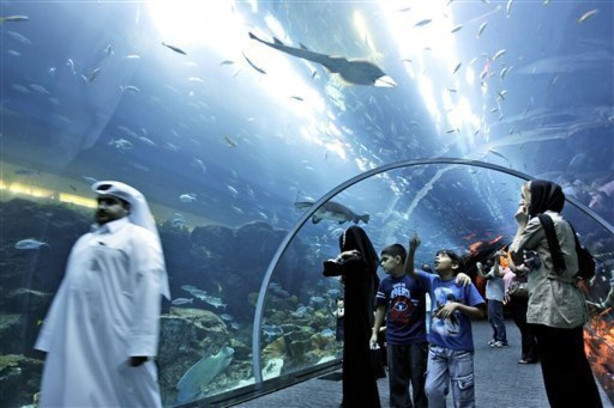 FILE - In this Wednesday, July 22, 2009 file photo, tourists and other people observe fish as they walk through the aquarium tunnel at the Dubai Mall in Dubai, United Arab Emirates. A large section of the Middle East's biggest shopping mall has been closed as maintenance crews scramble to contain a leak Thursday Feb. 25, 2010 at the massive, shark-filled aquarium there. An official at Dubai's civil defense department said "there has been a small break in the glass," and that rescue crews are on the scene. (AP Photo/Kamran Jebreili, File)