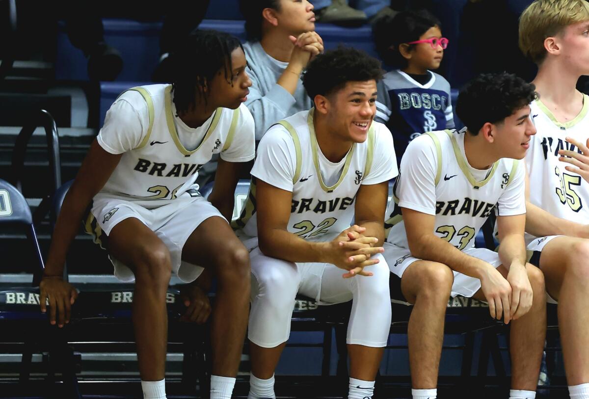St. John Bosco football standout Madden Williams (middle) sits on the bench with basketball teammates.