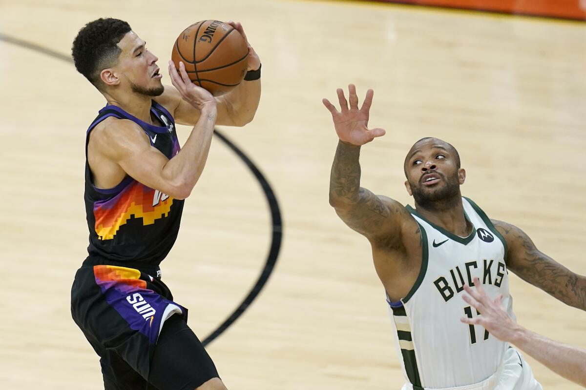 Phoenix Suns guard Devin Booker shoots against Milwaukee Bucks forward P.J. Tucker.