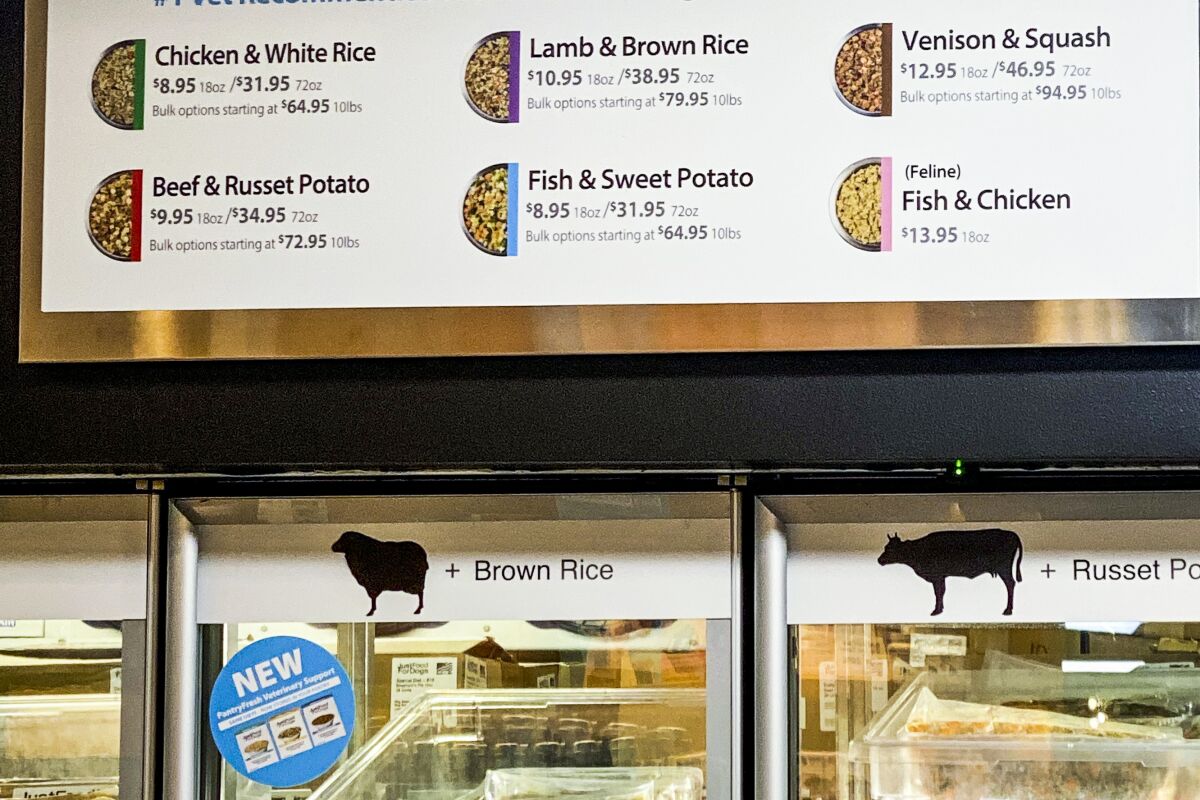 A sign describing dog food hangs over a refrigerated case