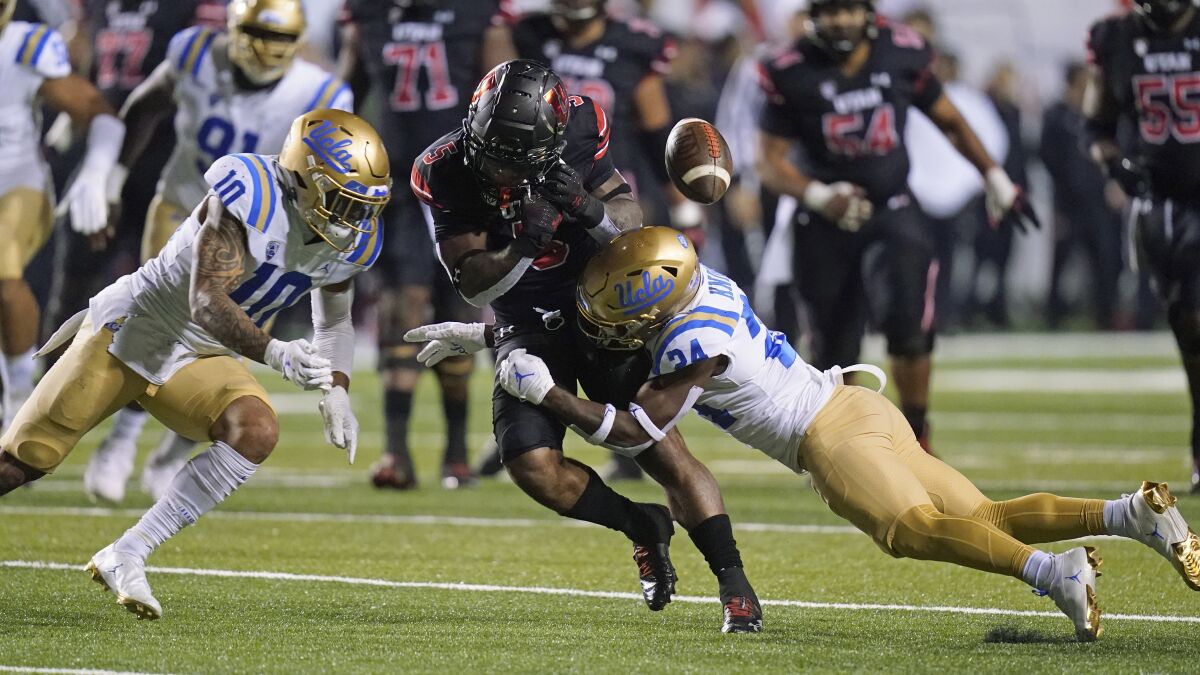Utah running back TJ Pledger loses control of the ball after a hit from UCLA's Qwuantrezz Knight.