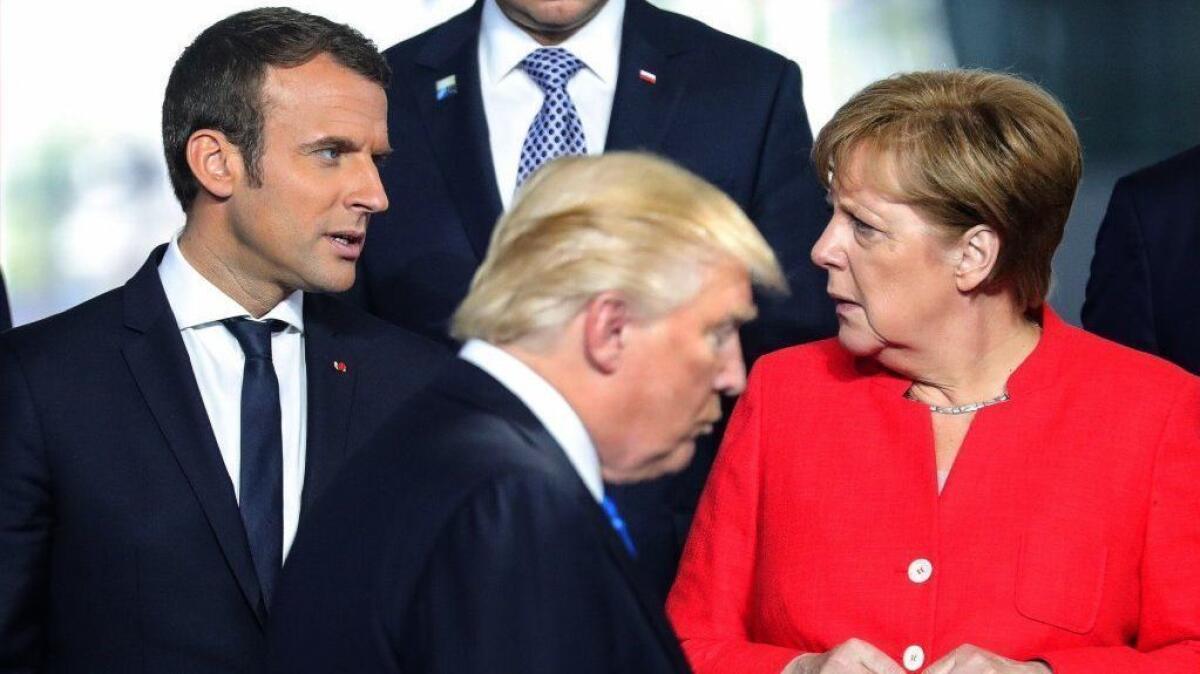French President Emmanuel Macron talks with German Chancellor Angela Merkel as President Trump walks by during the NATO summit in Brussels on May 25, 2017.