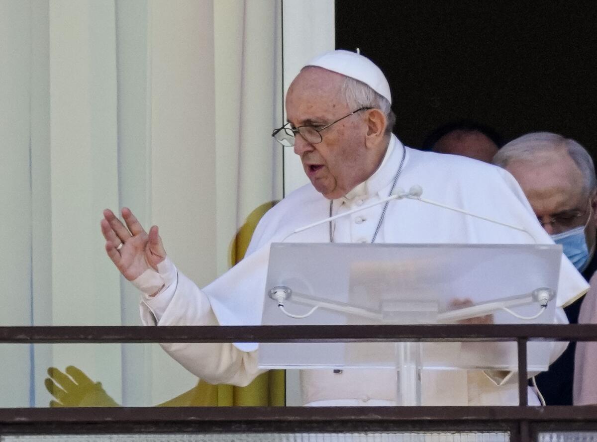 Pope Francis stands at a lectern. 