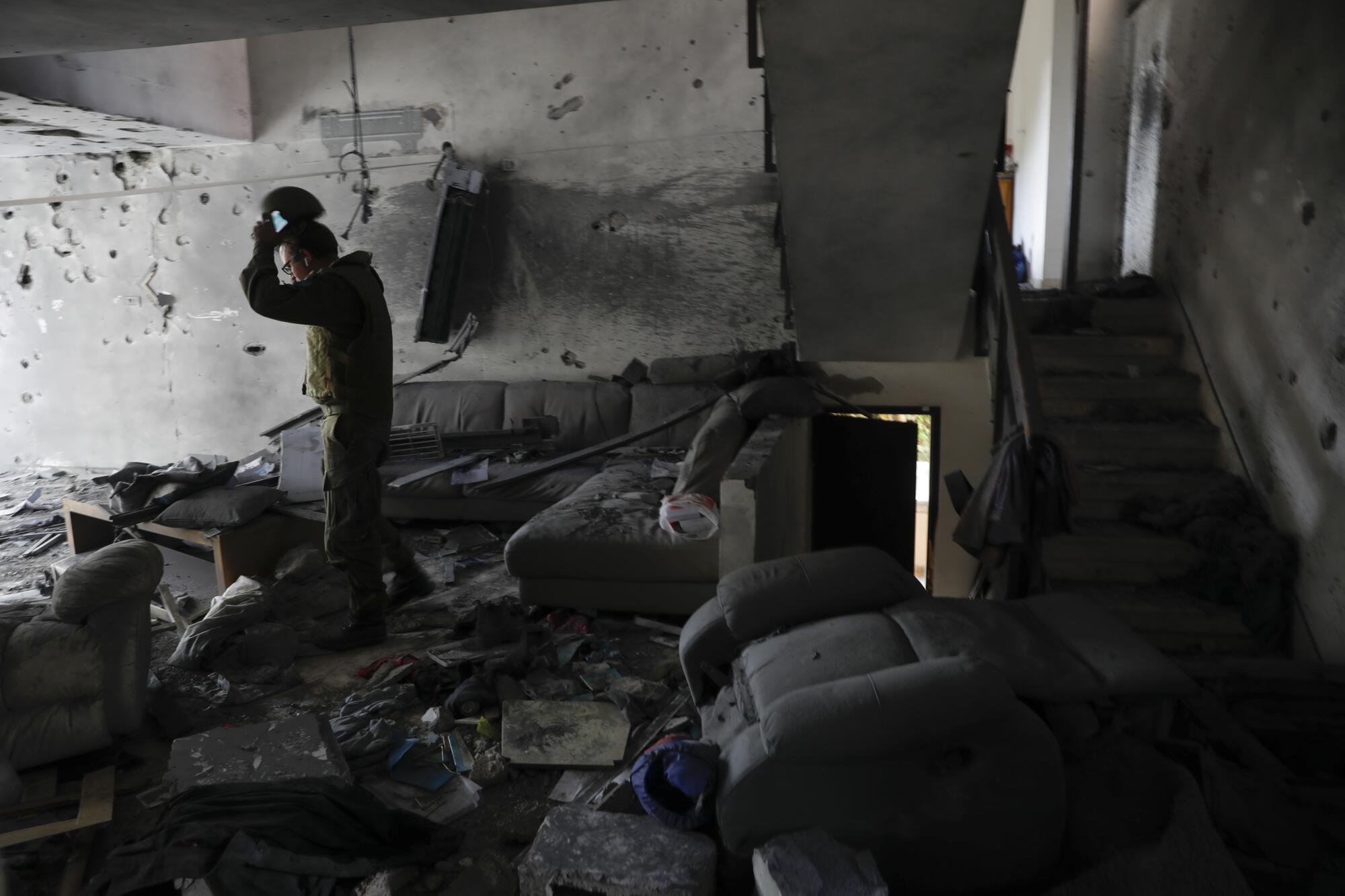 A soldier walks through the wreckage of a living room.