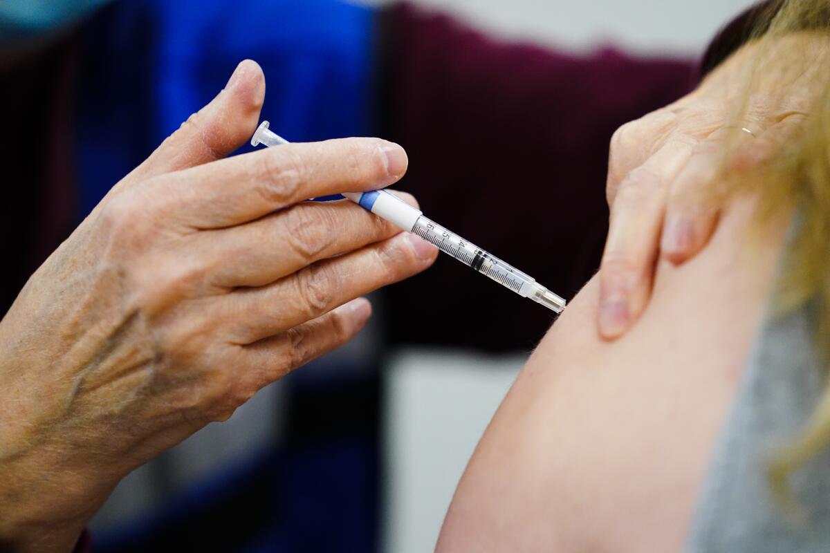 A health worker administers a dose of a COVID-19 vaccine during a vaccination clinic in Chester, Pa.