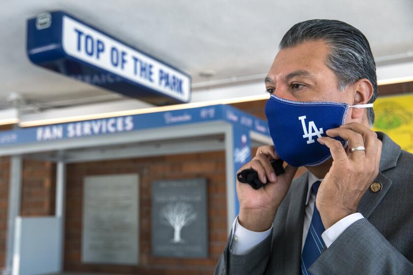 LOS ANGELES, CA - SEPTEMBER 24, 2020: California Secretary of State Alex Padilla puts on a Los Angeles Dodgers themed mask during a tour of the Dodger Stadium Vote Center, located on the Top Deck section of the stadium. The vote center will be open for early voting for for the general election, from October 30, 2020 to November 2, 2020, from 10am to 7pm and on Election Day from 7am to 8pm.. (Mel Melcon / Los Angeles Times)