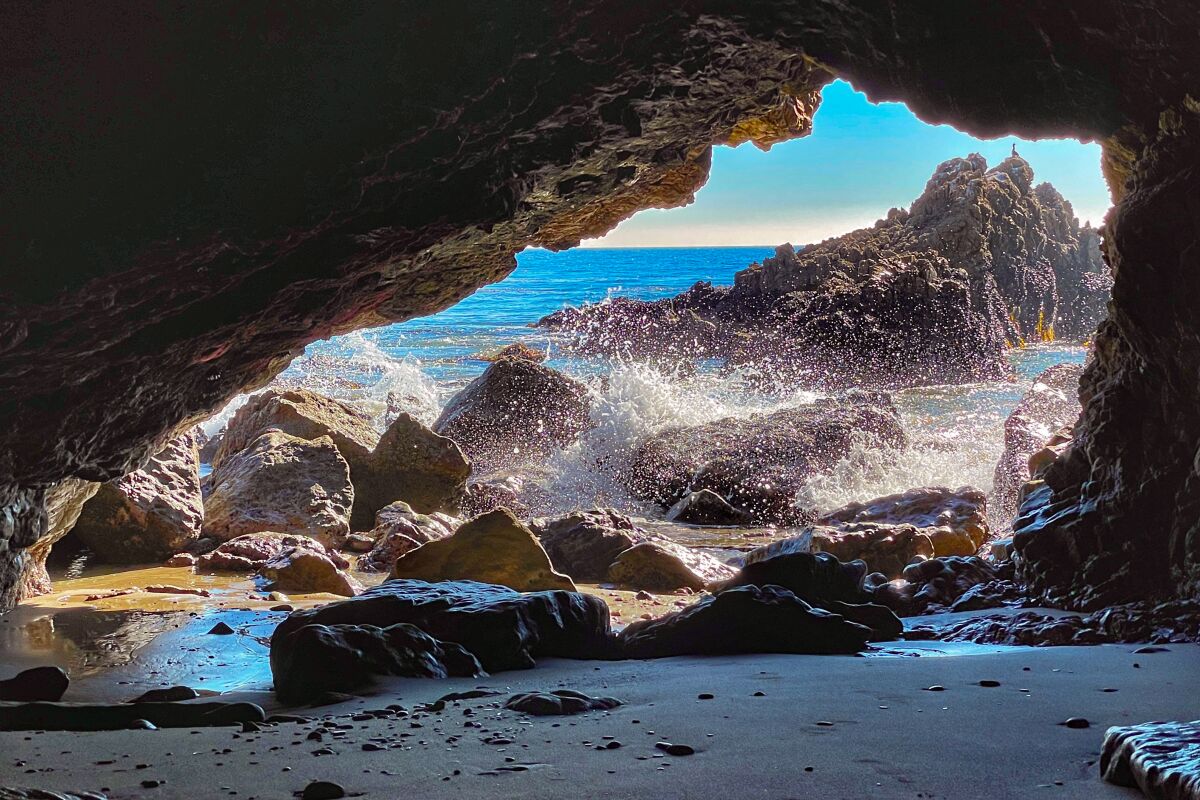 Waves splash onto rocks near the entrance to a sea cave.