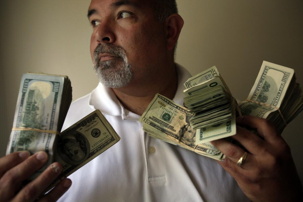 Butch Gupta, an investigator with the Mendocino County district attorney's office, holds about $45,000 in seized cash.