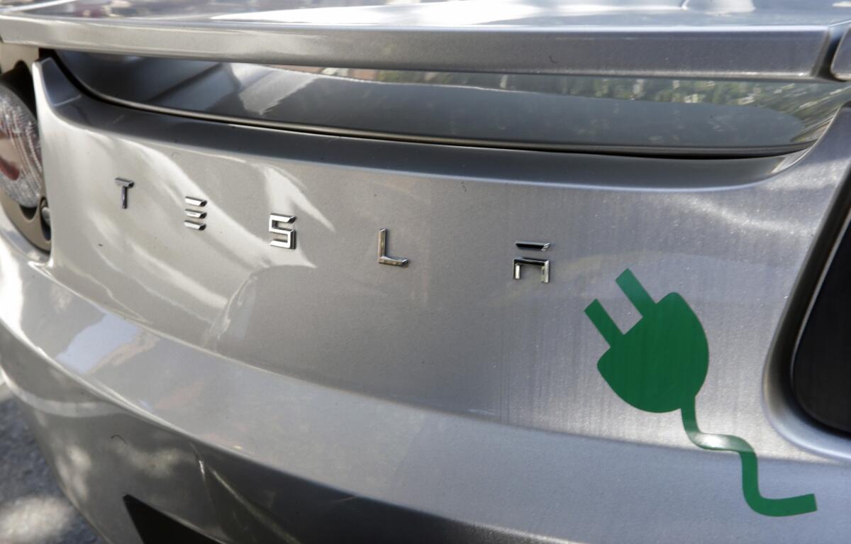 An electric plug decal is seen on the back of a Tesla electric car as owners, environmental and business advocates rally in front of the New Jersey statehouse Monday to call on legislators to pass a bill that will allow Tesla to resume sales in New Jersey.