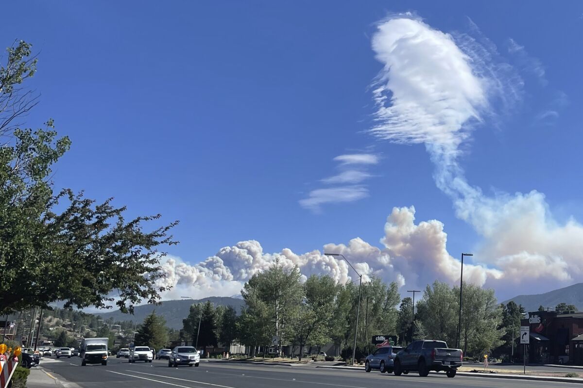 This photo taken Monday, June 13, 2022, and provided by Amanda Loftus shows smoke from a wildfire burning on the outskirts of Flagstaff, Arizona. The wind moderated on Tuesday giving firefighters some help in corralling the blaze. (Amanda Loftus via AP)