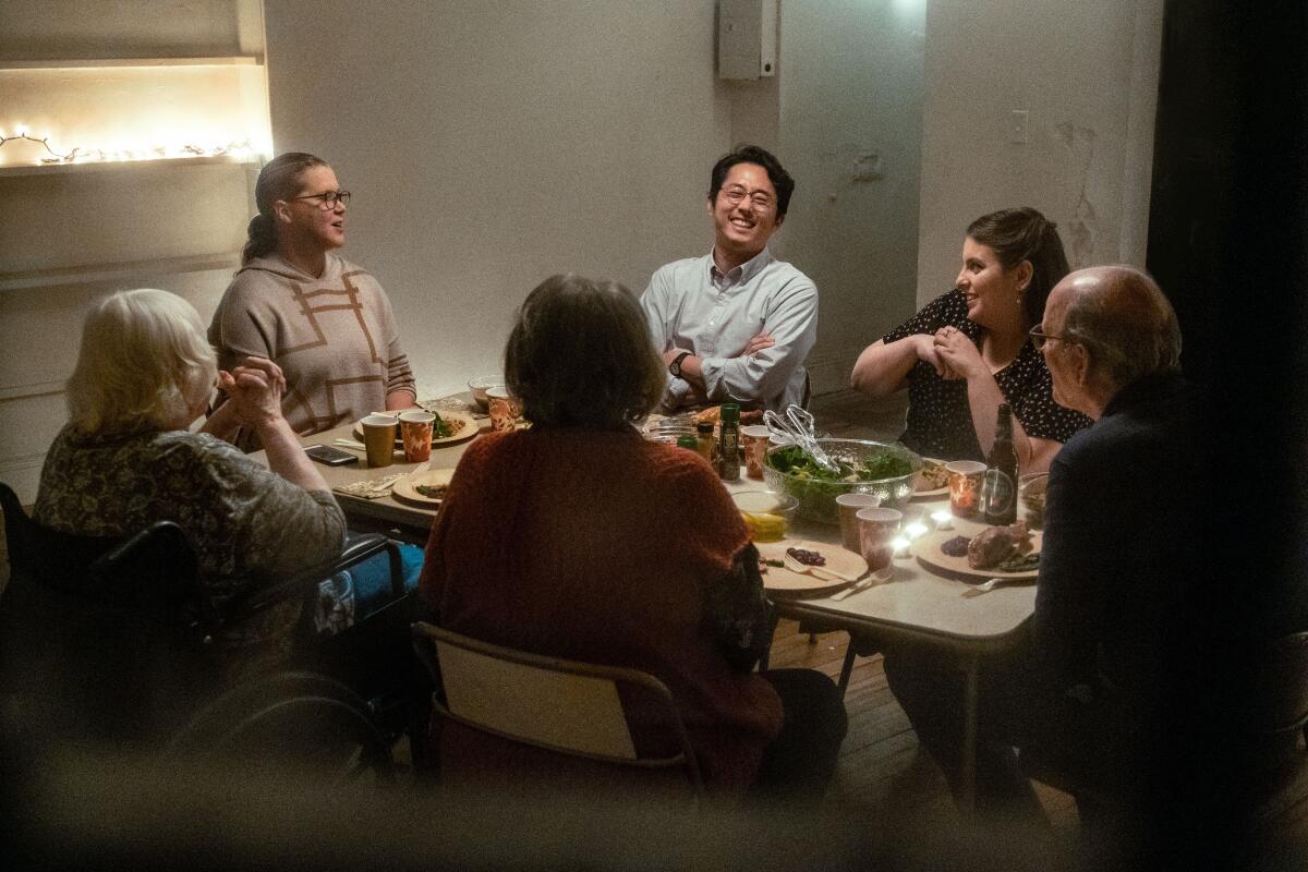 People talk and laugh around a table in the movie "The Humans."